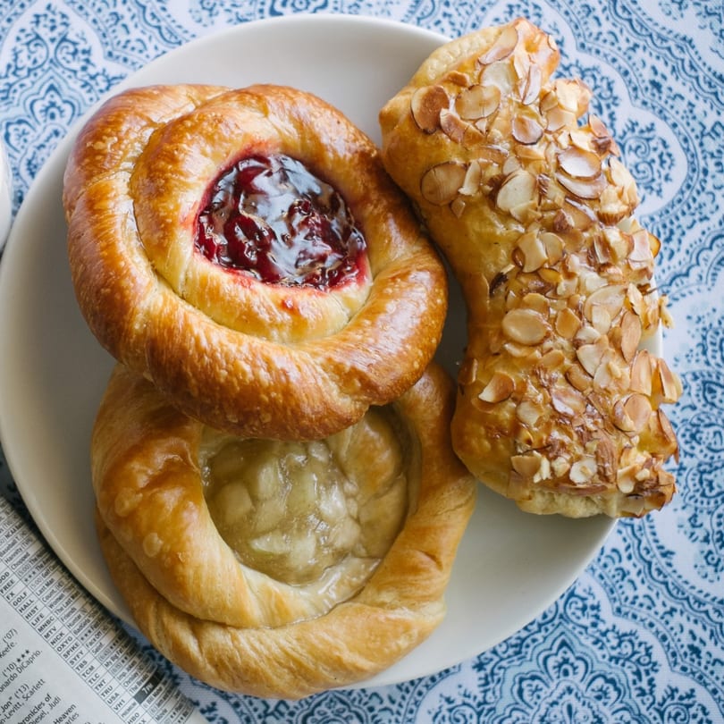 A plate of House of Bagels pastries, including two fruit-filled danishes and an almond pastry.